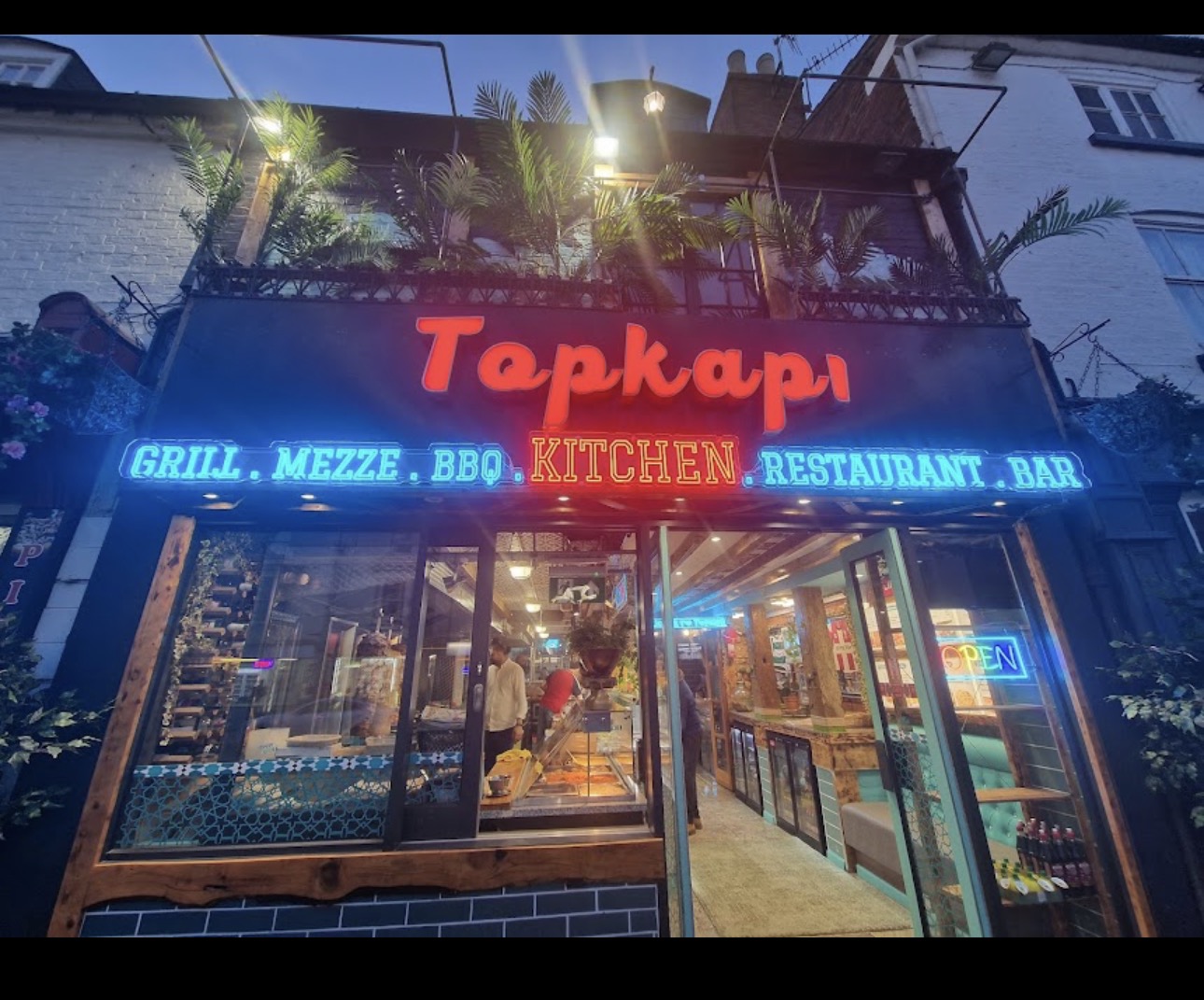 Topkapi Kitchen frontage with its red Topkapi sign, turquoise neon lettering and wooden entrance
